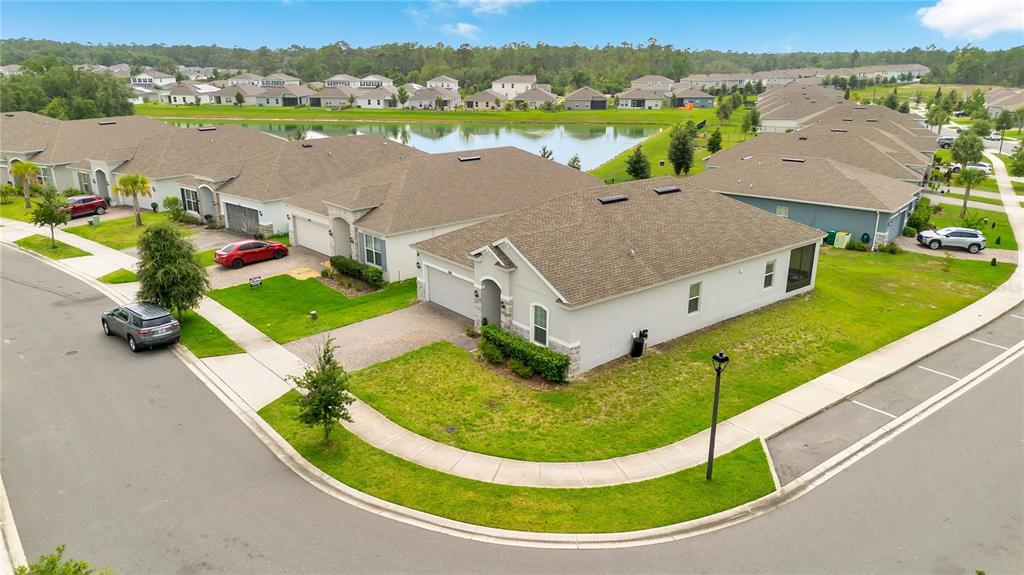 An aerial view shows a suburban neighborhood with single-family homes surrounding a central pond — 1065 CHELAN FALLS DRIVE, DELAND, FL