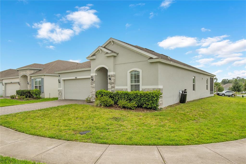 A single-story suburban house with a stucco exterior, stone accents, and a two-car garage — 1065 CHELAN FALLS DRIVE, DELAND, FL