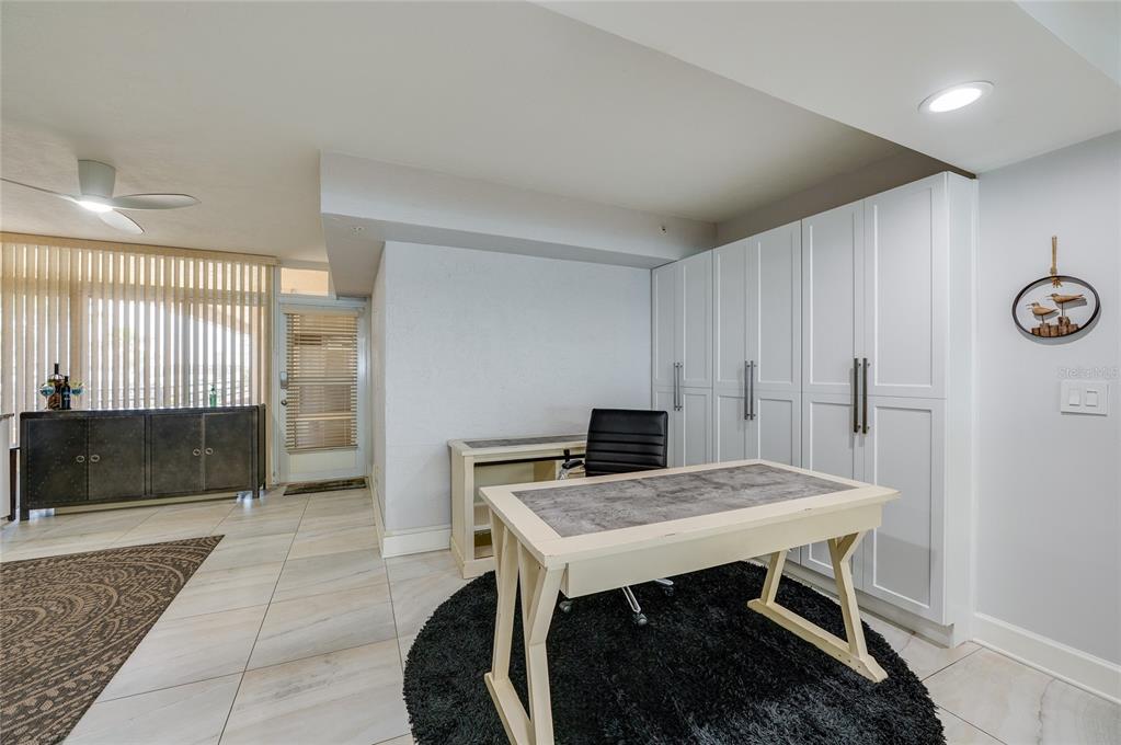 A home office features a desk on a circular rug, white cabinetry, and tile flooring — 4575 S ATLANTIC AVENUE UNIT 6304, PONCE INLET, FL