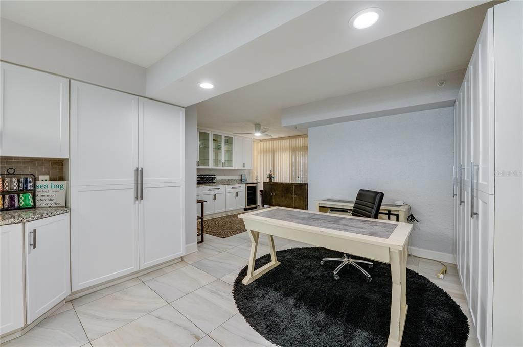 A home office features white cabinetry, a desk on a round rug, and tile flooring — 4575 S ATLANTIC AVENUE UNIT 6304, PONCE INLET, FL