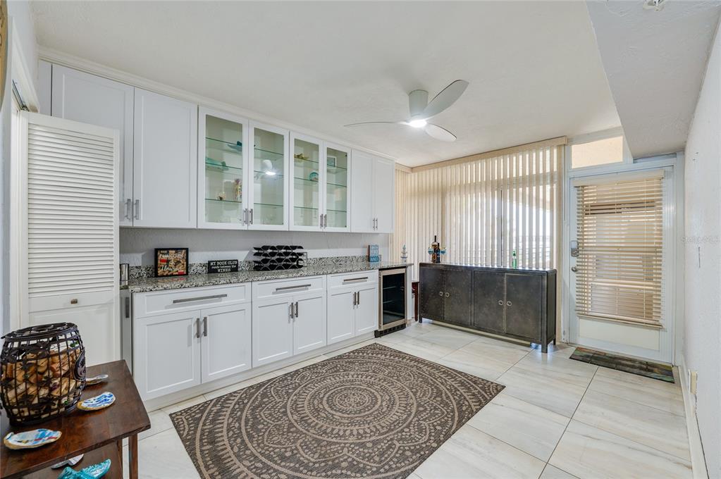 A wet bar features white cabinetry, granite countertops, a wine cooler, and a patterned area rug — 4575 S ATLANTIC AVENUE UNIT 6304, PONCE INLET, FL