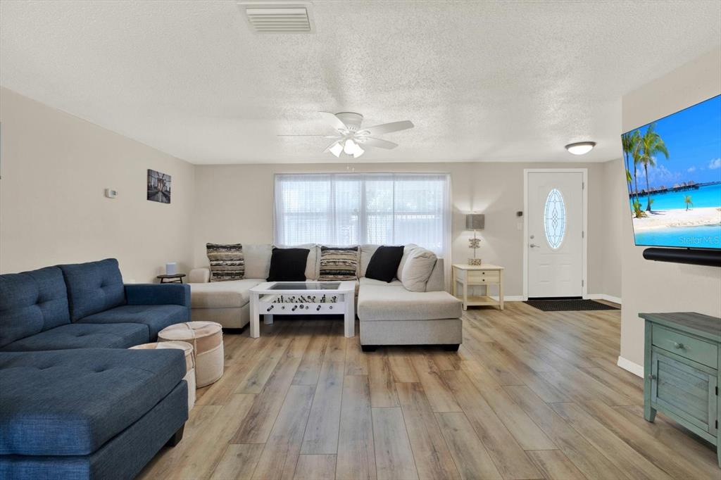 A living room features a sectional sofa, a foosball coffee table, and a wall-mounted television — 5642 DOVE DRIVE, NEW PORT RICHEY, FL