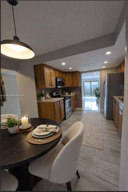 A dining area with a round table opens into a kitchen featuring wood cabinets — 3530 NW 98th Ter # 5H, Sunrise FL 33351, SUNRISE, FL