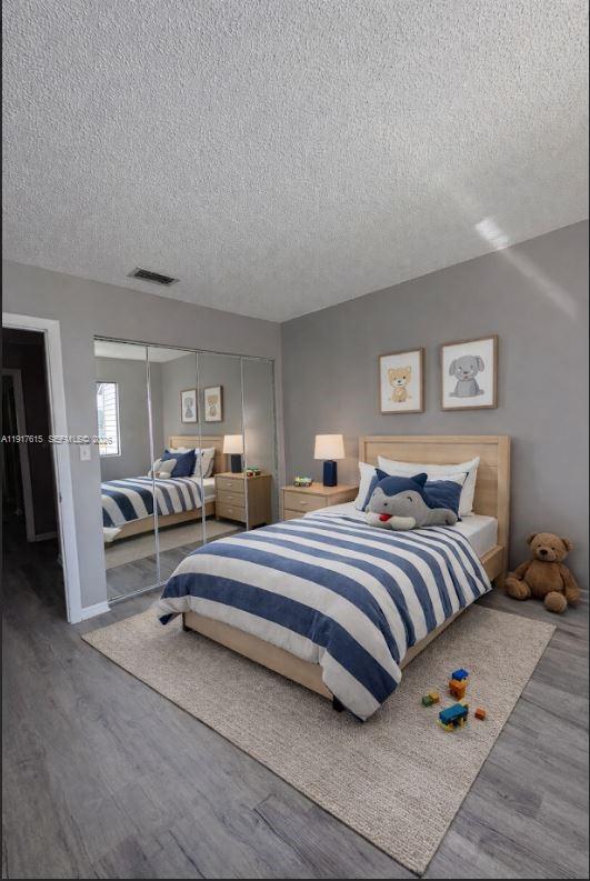 A bedroom features a light wood bed with a striped comforter, mirrored closet, and gray walls — 3530 NW 98th Ter # 5H, Sunrise FL 33351, SUNRISE, FL