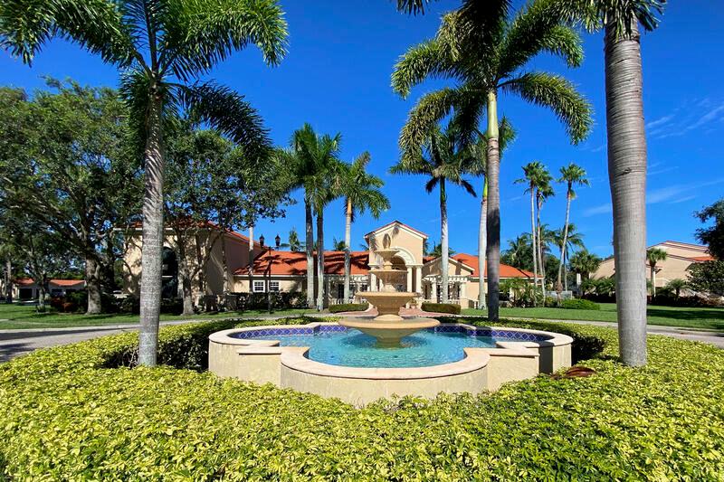 A tiered stone fountain sits in front of a large building surrounded by palm trees — VERO BEACH, FL