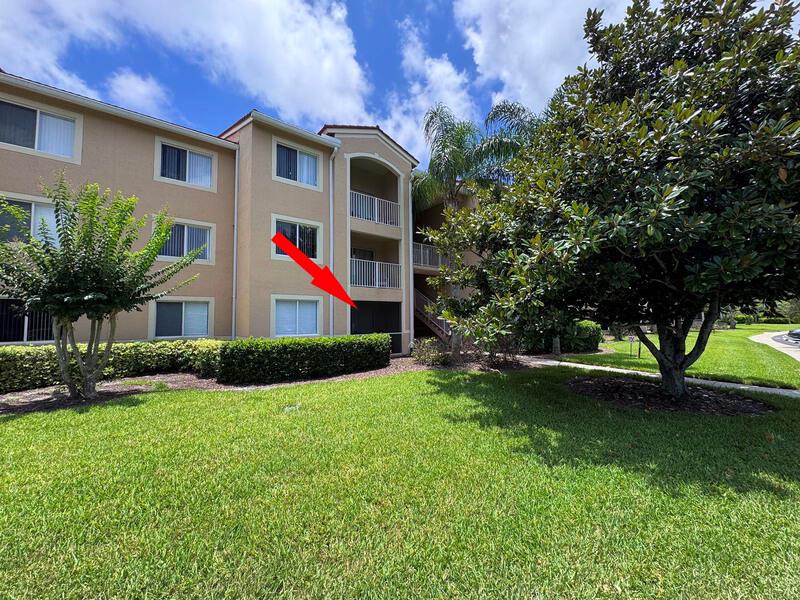 A three-story apartment building exterior features a ground-floor screened patio marked by a red arrow — VERO BEACH, FL