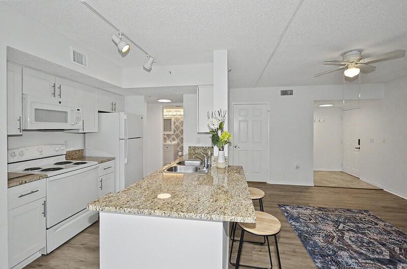 A kitchen with white cabinets, granite countertops, and an island with two stools — VERO BEACH, FL