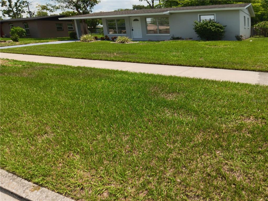 A single-story house with a gray exterior, white door, and a large front lawn — 2103 MANTILLA AVENUE, ORLANDO, FL