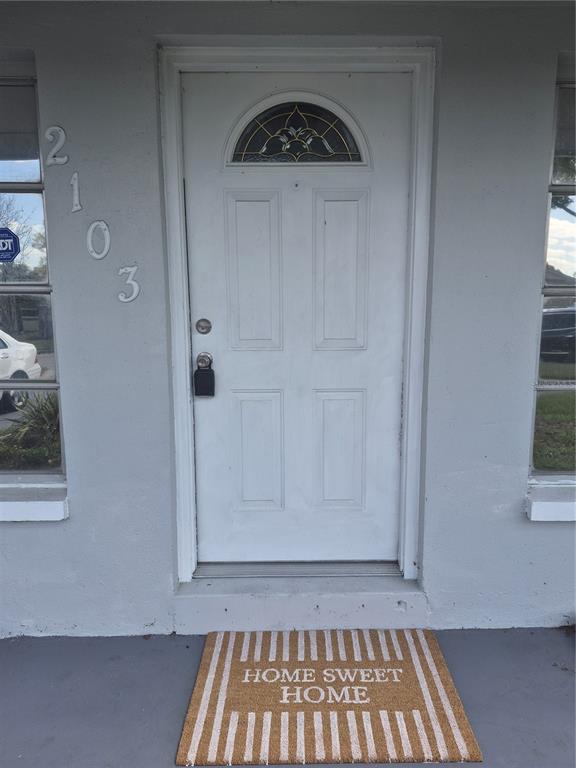 A white front door with a glass arch window sits between two windows on a house — 2103 MANTILLA AVENUE, ORLANDO, FL