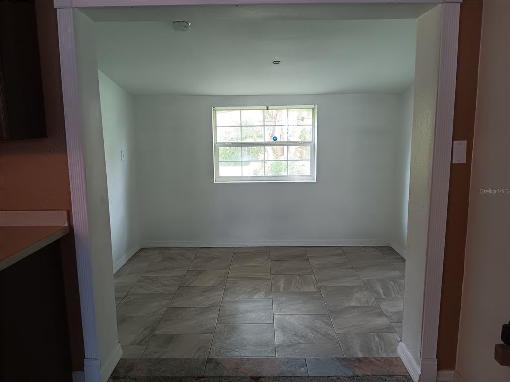 A small dining area with light-colored tile flooring and a single window on the back wall — 2103 MANTILLA AVENUE, ORLANDO, FL