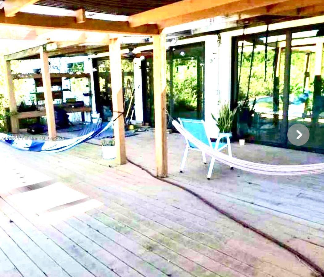 A wooden deck features a hammock, a lounge chair, and a covered patio area — 312 St, Homestead FL 33033, HOMESTEAD, FL