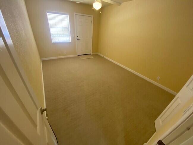 An empty room with beige carpet, yellow walls, a ceiling fan, and a white door — 135 NW 5th Avenue # 3, Delray Beach FL 33444, DELRAY BEACH, FL