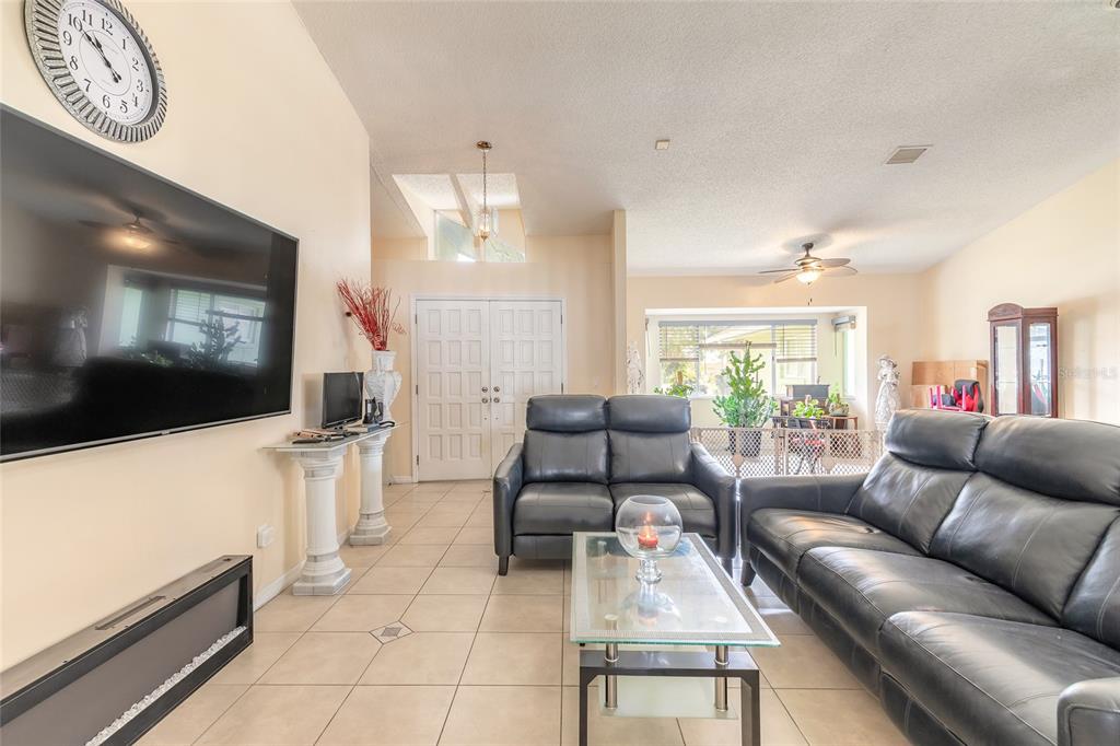 A living room features tile flooring, black leather sofas, a large television, and a ceiling fan — 50 FLORIDA PARK DRIVE, PALM COAST, FL