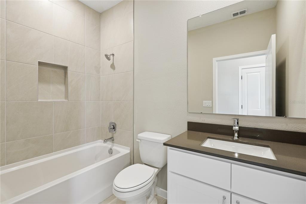A bathroom featuring a white vanity, a toilet, and a tiled bathtub-shower combination — 4532 NW 37TH STREET RD, OCALA, FL