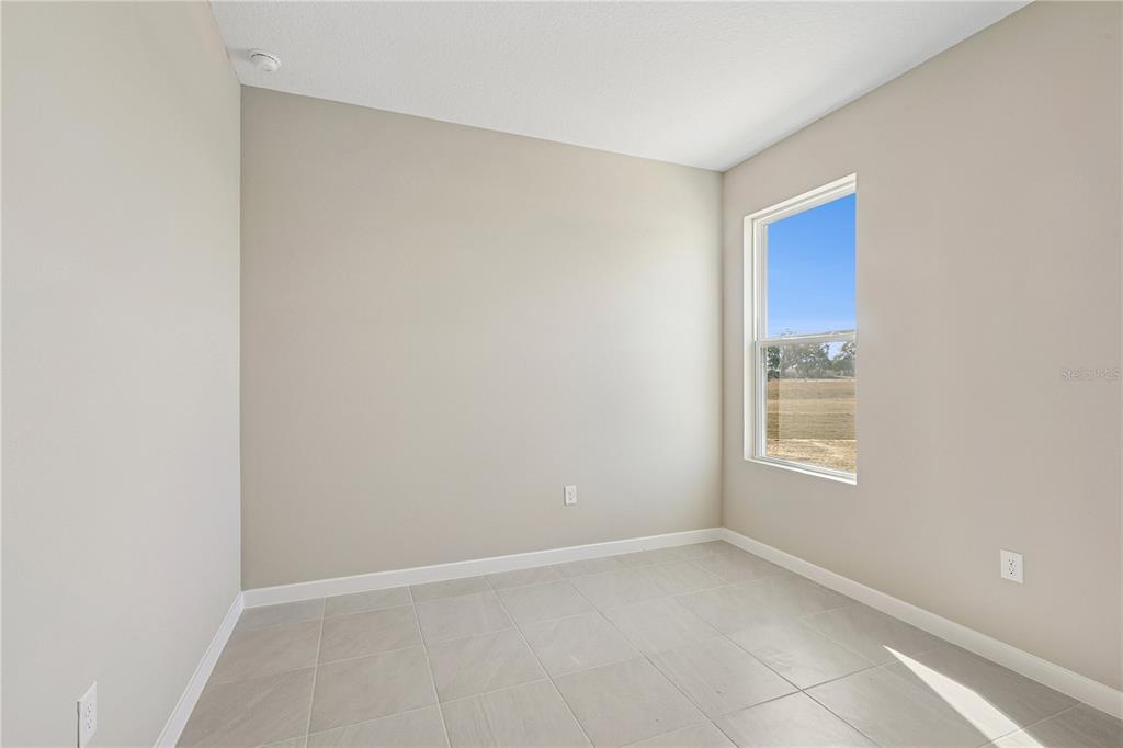 An empty room with beige walls, light-colored tile flooring, and a single window — 4532 NW 37TH STREET RD, OCALA, FL