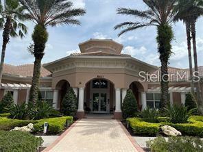 A paved walkway leads to the arched entrance of a tan building with palm trees — 1357 VENEZIA COURT UNIT 302, DAVENPORT, FL