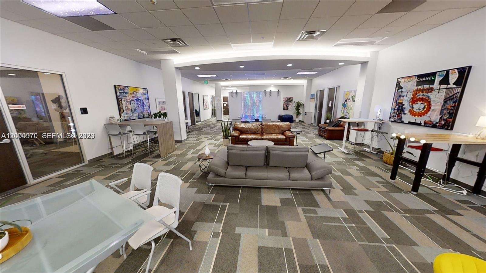 A modern office lounge area features two sofas, a glass table, and patterned carpet flooring — 1501 Biscayne Blvd # 501D, Miami FL 33132, MIAMI, FL