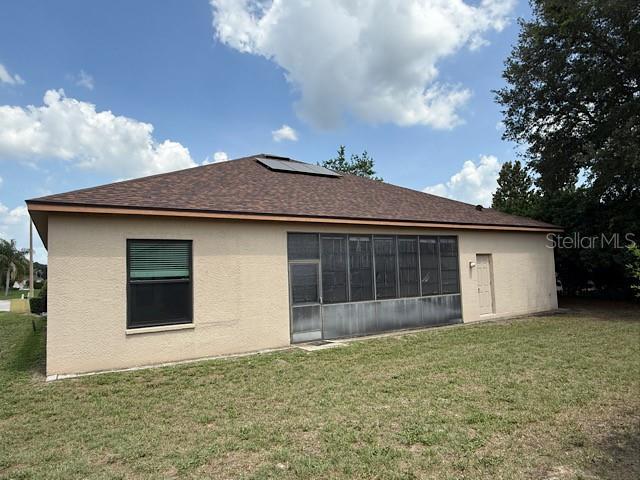 The exterior of a beige house features a screened-in porch and a dark shingled roof — 13743 BRYNDLEWOOD COURT, HUDSON, FL