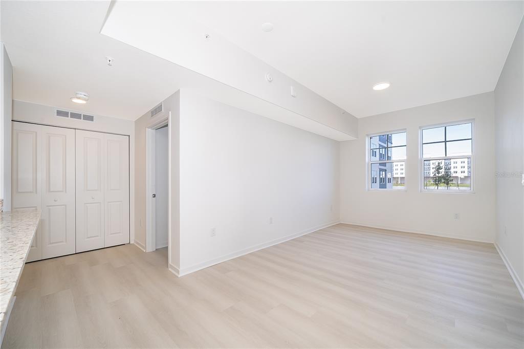 An empty room with light wood-look flooring, white walls, a closet, and two windows — 5587 MILLENIA PARK BLVD UNIT 113, ORLANDO, FL