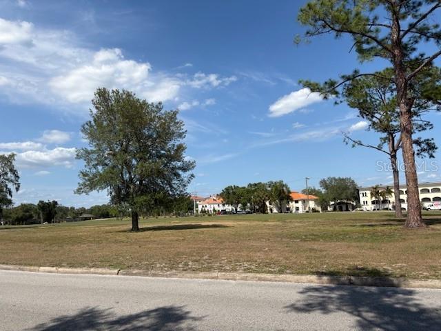A grassy, open lot features scattered trees with buildings visible in the background — 112 N LOCKMOOR AVENUE, TEMPLE TERRACE, FL