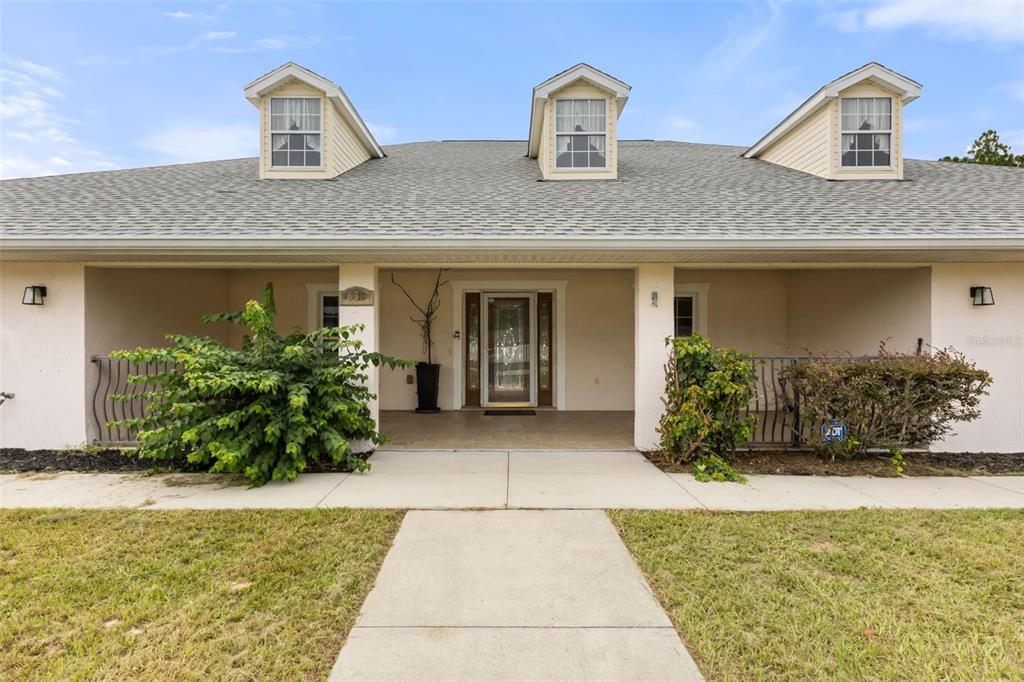 A single-story house exterior features a covered porch, three dormer windows, and a concrete walkway — 639 MARION OAKS TRAIL, OCALA, FL