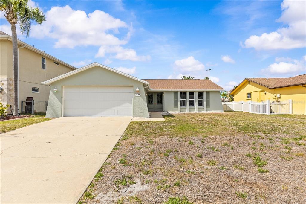 A single-story house with a light green exterior, a two-car garage, and a concrete driveway — 7427 SOUTHWIND DRIVE, HUDSON, FL
