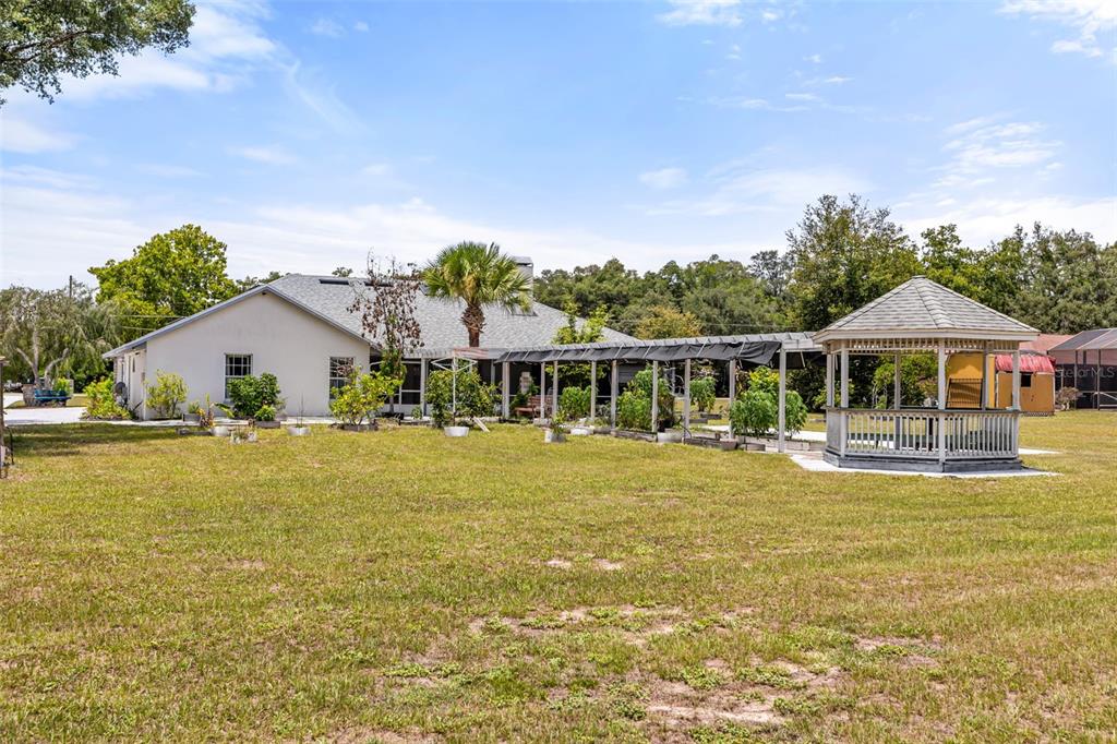 A backyard features a house, a gazebo, and a long, covered garden structure — 6231 ALBETH ROAD, ORLANDO, FL