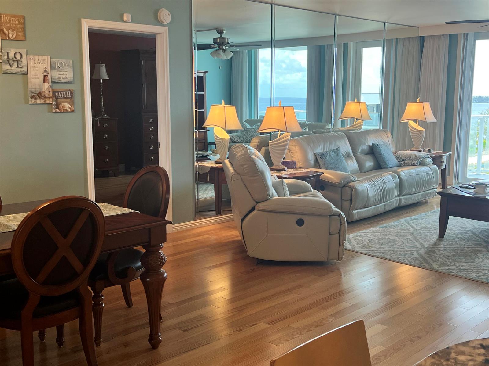A living room features light-colored leather furniture, a mirrored wall, and hardwood flooring — 3450 S Ocean Boulevard Boulevard # 701, Palm Beach FL 33480, PALM BEACH, FL
