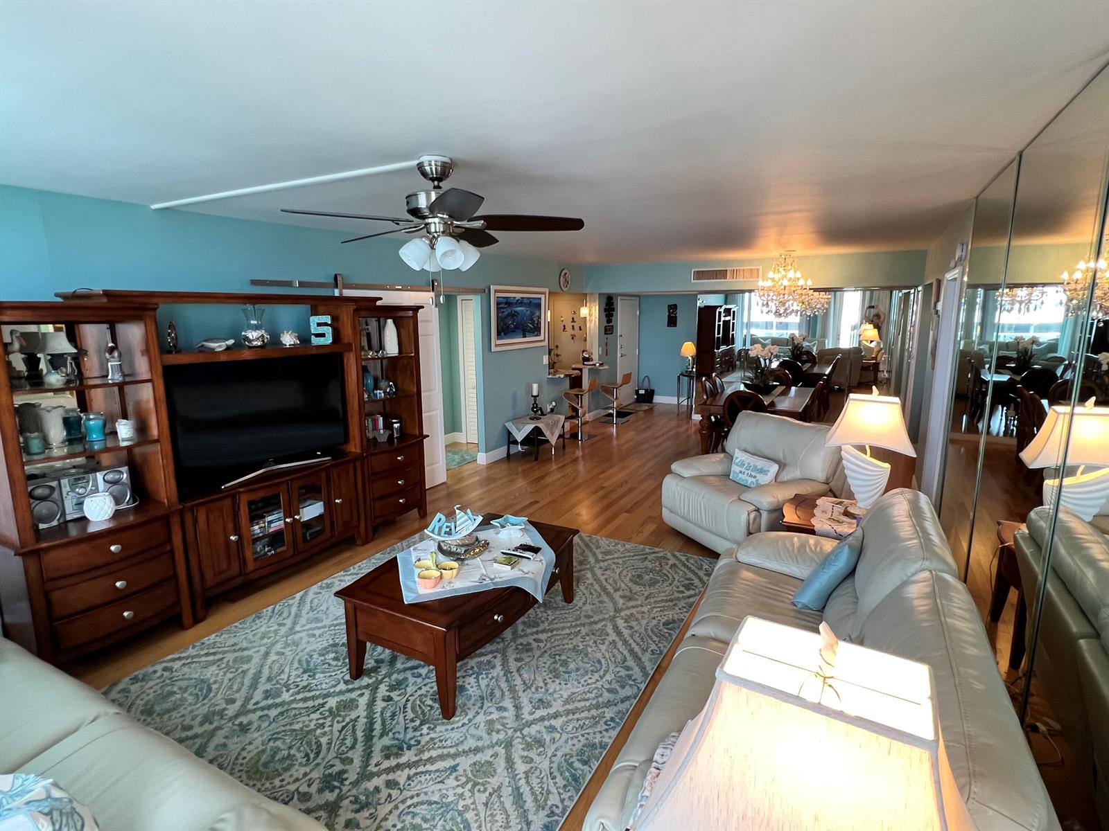 A living room with wood floors, a large entertainment center, and a patterned area rug — 3450 S Ocean Boulevard Boulevard # 701, Palm Beach FL 33480, PALM BEACH, FL