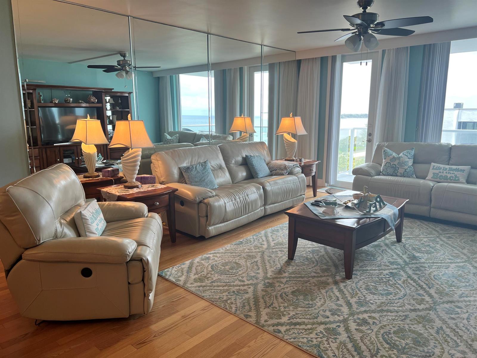 A living room with light leather furniture, a patterned rug, and a mirrored wall — 3450 S Ocean Boulevard Boulevard # 701, Palm Beach FL 33480, PALM BEACH, FL
