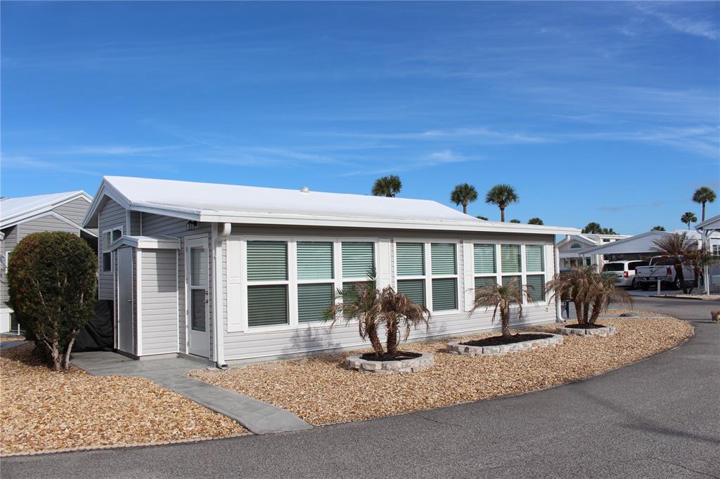 A light gray manufactured home with a white roof sits on a gravel lot — 9000 US HWY 192 UNIT 598, CLERMONT, FL