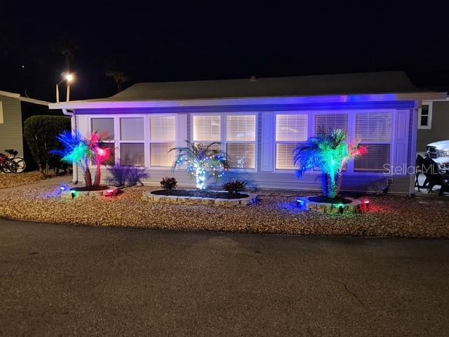 A single-story house exterior at night features illuminated palm trees and decorative lighting — 9000 US HWY 192 UNIT 598, CLERMONT, FL
