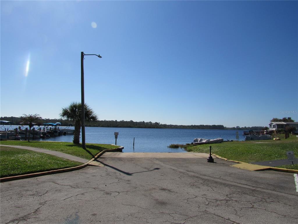 A paved boat ramp leads into a lake with docked boats and a palm tree — 9000 US HWY 192 UNIT 598, CLERMONT, FL