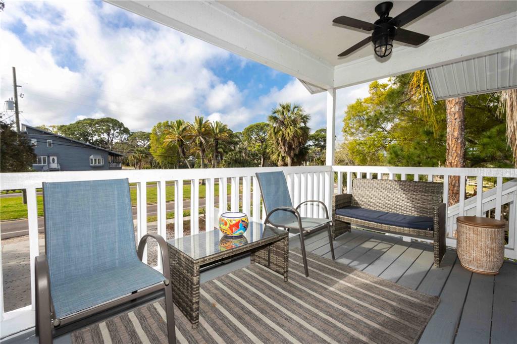 A covered wooden deck features outdoor furniture, a ceiling fan, and a view of trees — 815 FLORIDA AVENUE, PALM HARBOR, FL