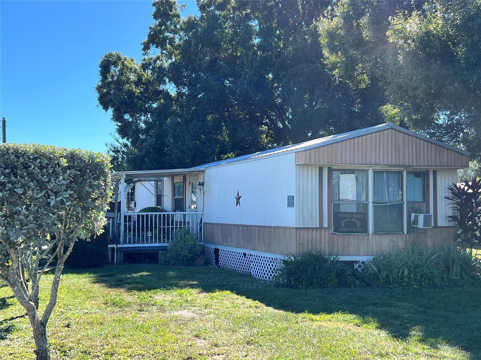 A single-story mobile home with a front porch, a metal star, and a warning sign — 3438 SE 27th Street, Okeechobee FL 34974, OKEECHOBEE, FL