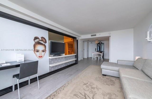 A living room features a desk, a wall-mounted television, and a light-colored sectional sofa — 1100 West Ave # 721, Miami Beach FL 33139, MIAMI BEACH, FL