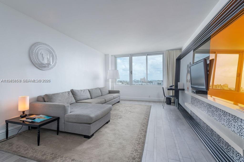 A living room features a grey sectional sofa, a rug, and a wall-mounted television — 1100 West Ave # 721, Miami Beach FL 33139, MIAMI BEACH, FL