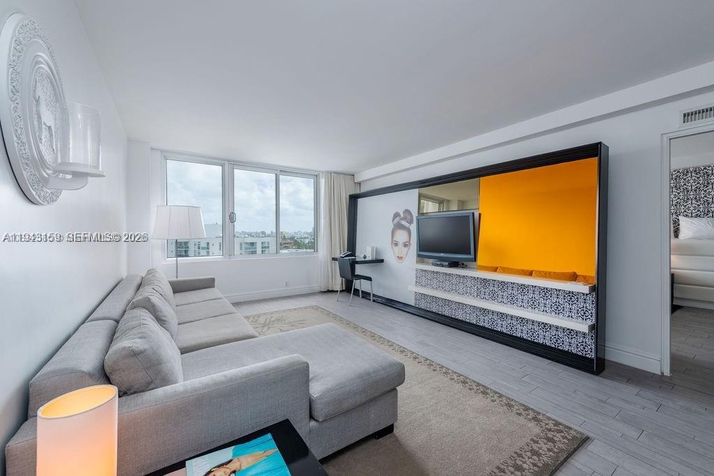 A living room features a gray sectional sofa, a wall-mounted television, and a desk area — 1100 West Ave # 721, Miami Beach FL 33139, MIAMI BEACH, FL