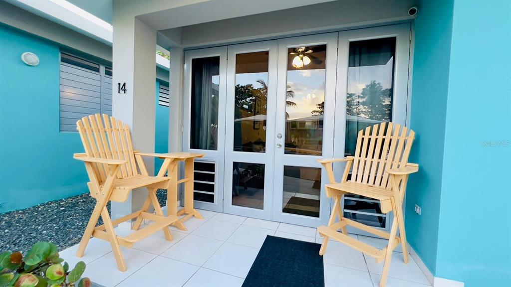 A patio with two wooden chairs sits outside a building with turquoise walls — KM 2.6 CARR 441 VILLA 14, AGUADA, PR