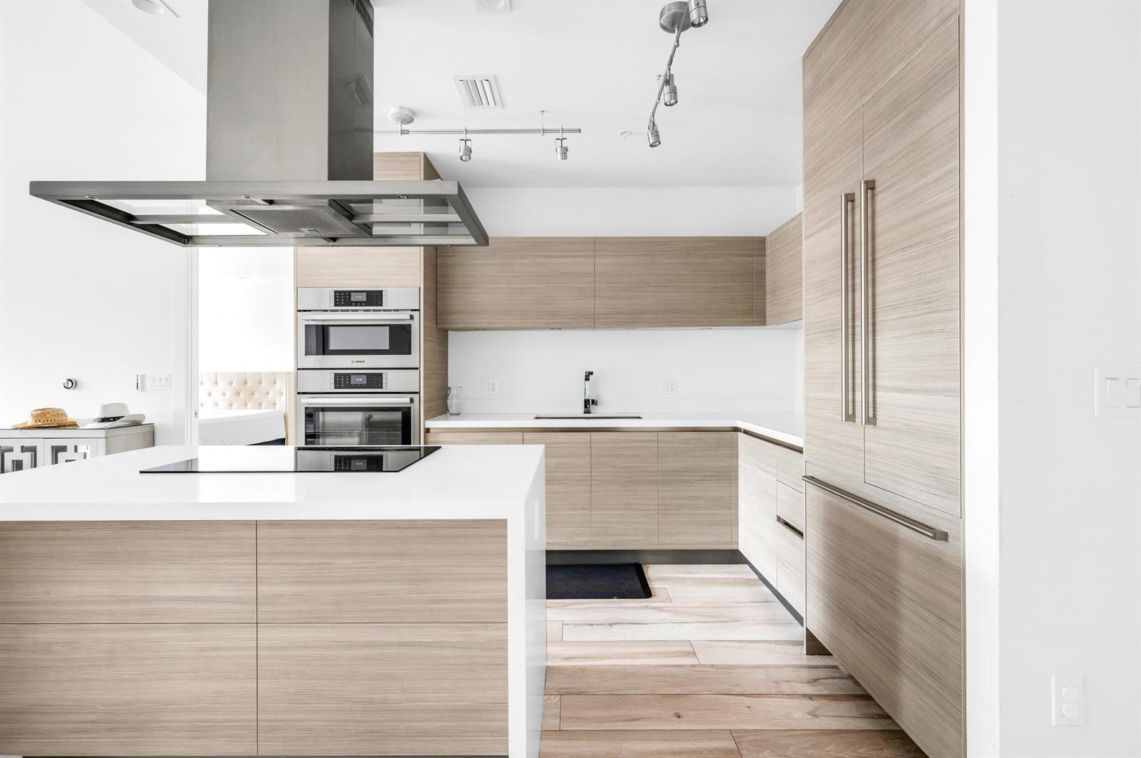 A modern kitchen features light wood cabinetry, a white island, and stainless steel appliances — 155 E Boca Raton Road # 418, Boca Raton FL 33432, BOCA RATON, FL