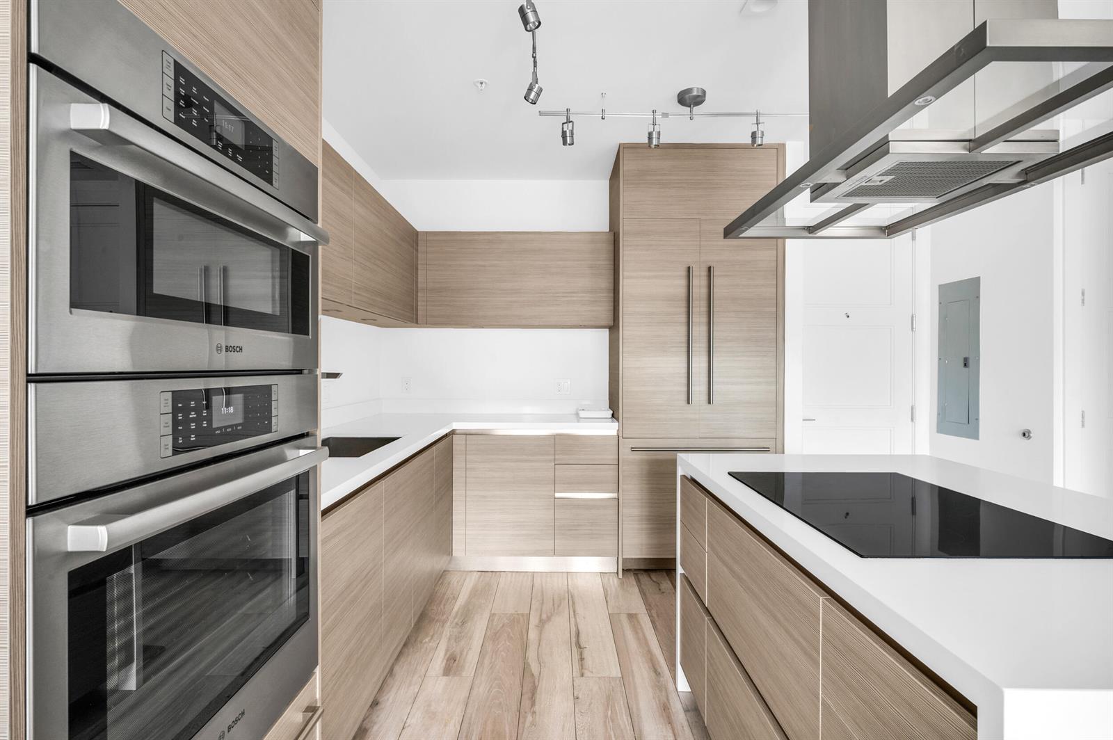 A modern kitchen features light wood cabinetry, stainless steel appliances, and a white countertop island — 155 E Boca Raton Road # 418, Boca Raton FL 33432, BOCA RATON, FL