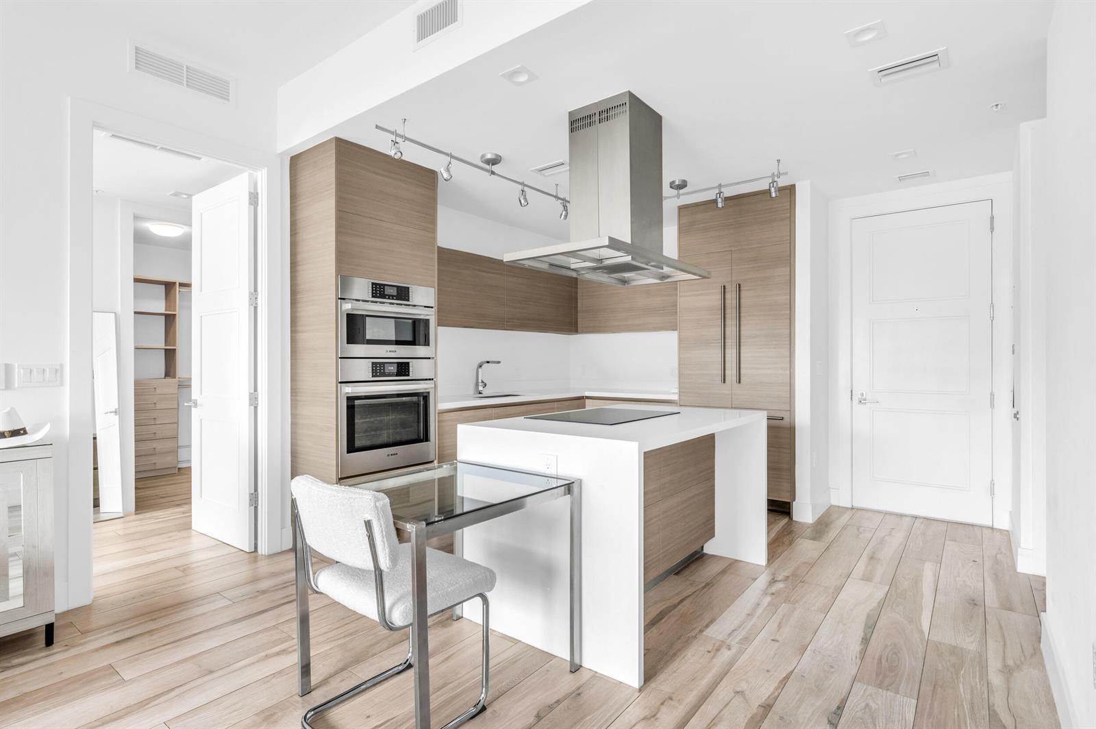 A modern kitchen features light wood cabinetry, a white island, and stainless steel appliances — 155 E Boca Raton Road # 418, Boca Raton FL 33432, BOCA RATON, FL