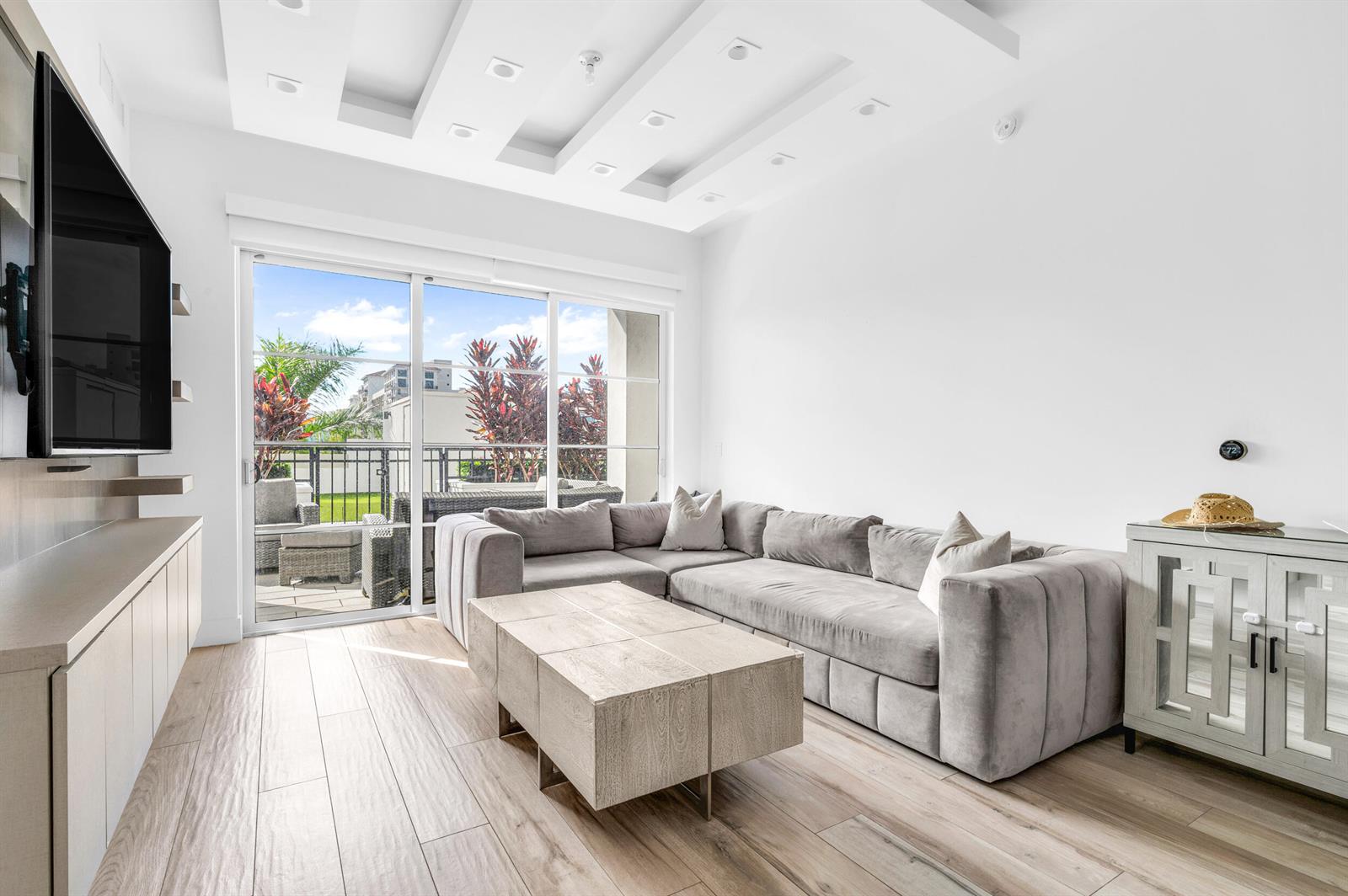 A modern living room features a gray sectional sofa, wood coffee table, and sliding glass doors — 155 E Boca Raton Road # 418, Boca Raton FL 33432, BOCA RATON, FL