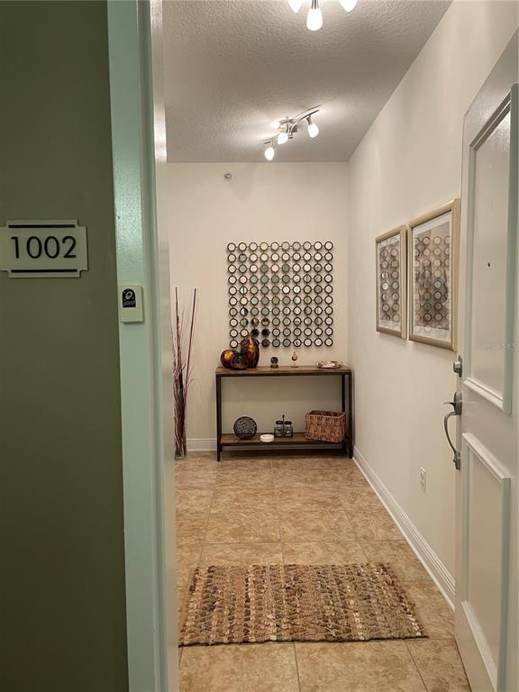 An entryway features tile flooring, a console table, wall art, and a door labeled 1002 — 628 CLEVELAND STREET UNIT 1002, CLEARWATER, FL