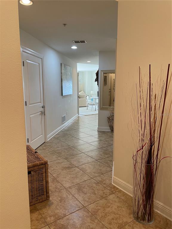 A tiled hallway leads from a foreground entryway toward a bright, open living area — 628 CLEVELAND STREET UNIT 1002, CLEARWATER, FL