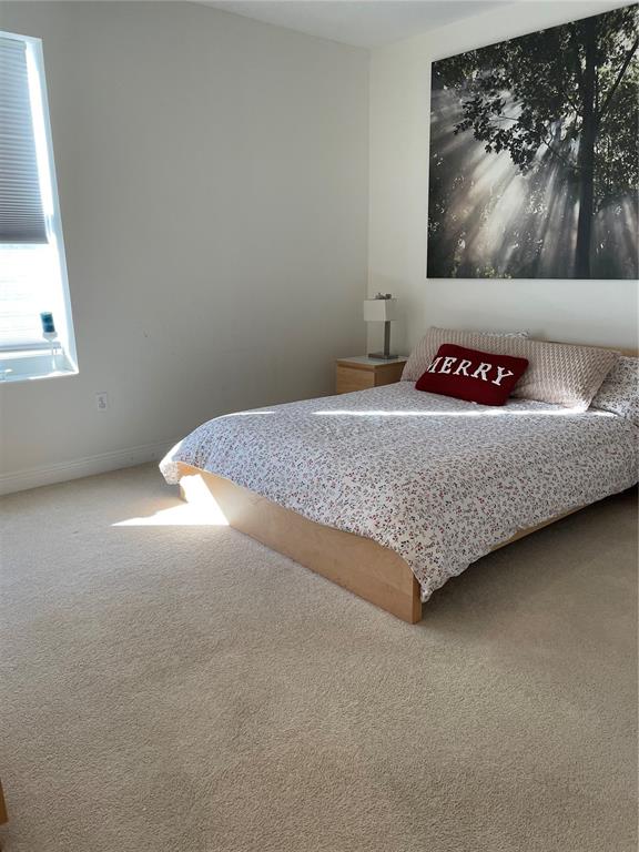 A bedroom features light carpet, a platform bed with patterned bedding, and wall art — 628 CLEVELAND STREET UNIT 1002, CLEARWATER, FL