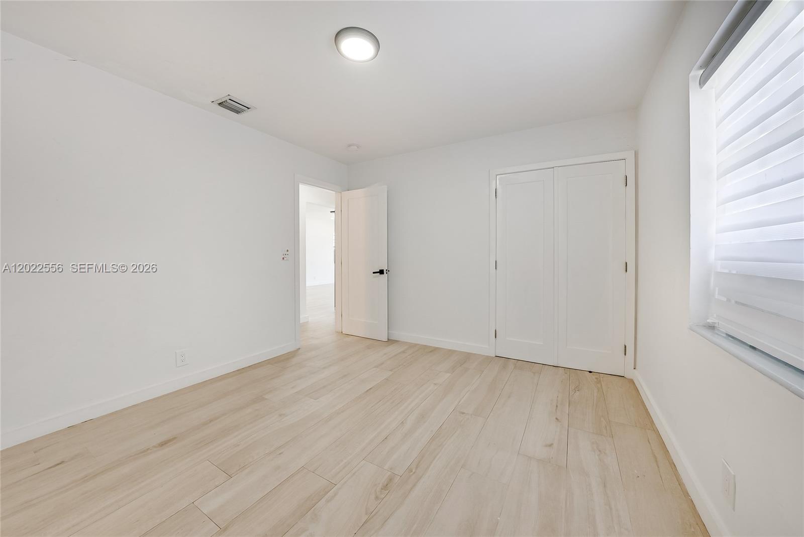 A bedroom with white walls, light wood-look flooring, a closet, and a window with blinds — 716 SW 5th Ave, Hallandale Beach FL 33009, HALLANDALE BEACH, FL