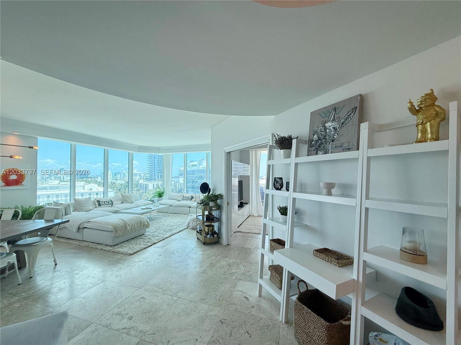 A bright living room features white tile floors, a large sectional sofa, and floor-to-ceiling windows — 300 S Pointe Dr # 705, Miami Beach FL 33139, MIAMI BEACH, FL