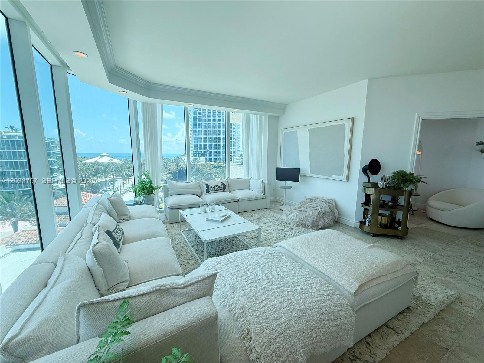 A bright living room features a large sectional sofa, white coffee table, and floor-to-ceiling windows — 300 S Pointe Dr # 705, Miami Beach FL 33139, MIAMI BEACH, FL