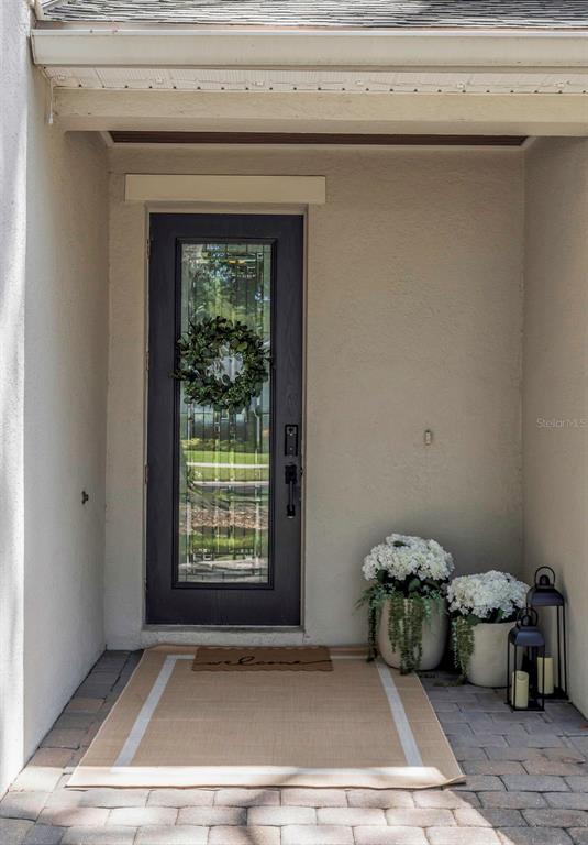 A dark front door with a glass insert and wreath sits on a paved porch — 4109 W VASCONIA STREET, TAMPA, FL